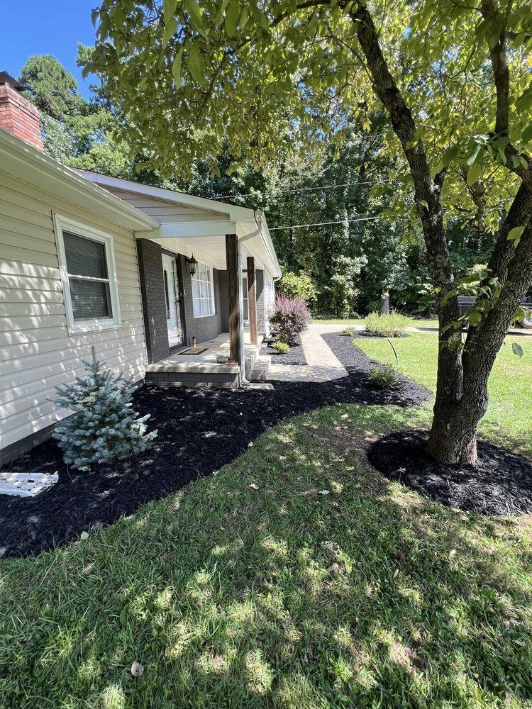 A house with a porch and a tree in front of it.