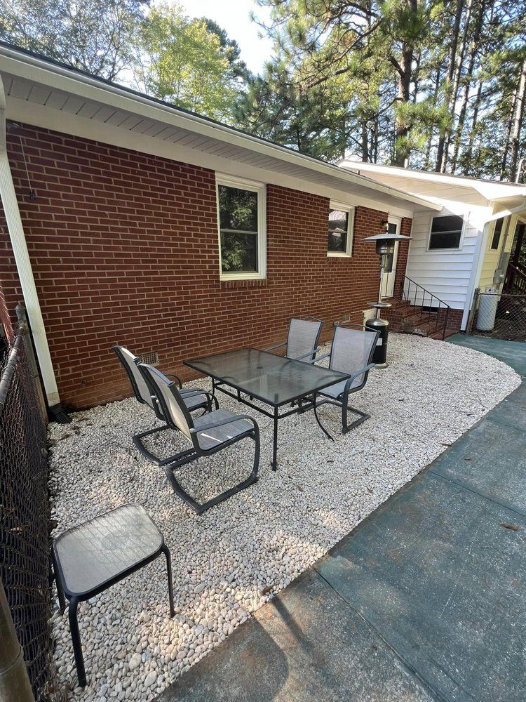 A patio with a table and chairs in front of a brick house.