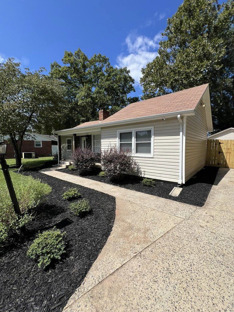 A small white house with a red roof and a walkway leading to it.