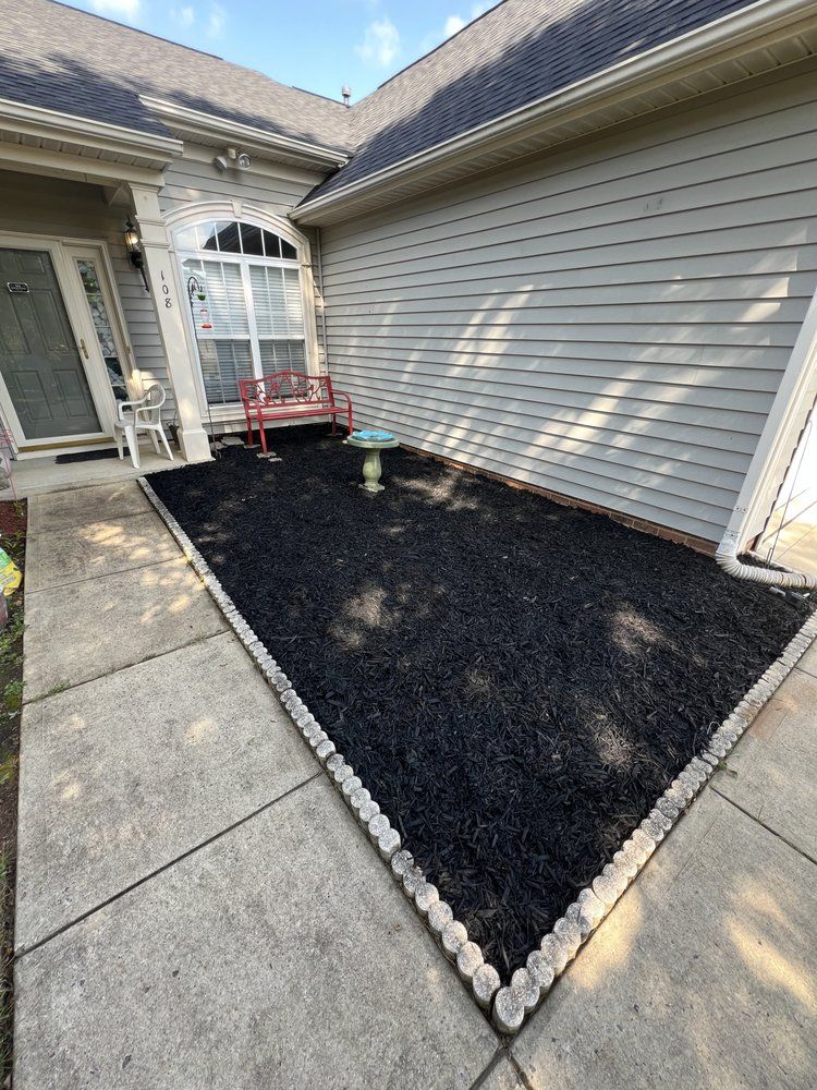 A patio with a bench and a bird bath in front of a house.