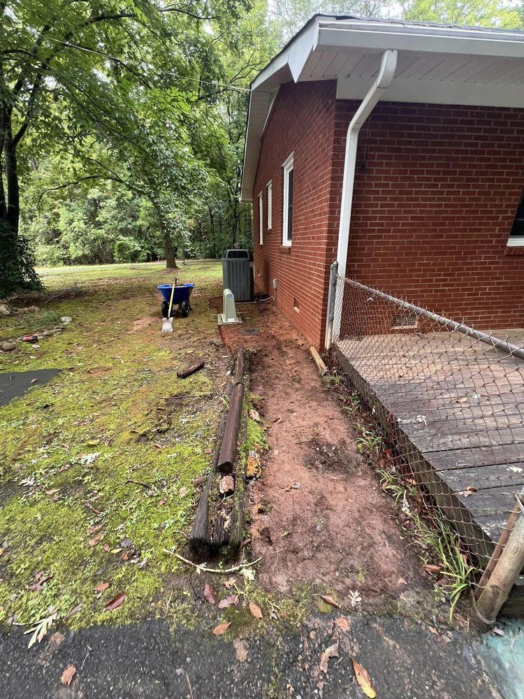 A brick house with a ramp in front of it is sitting on top of a dirt field.