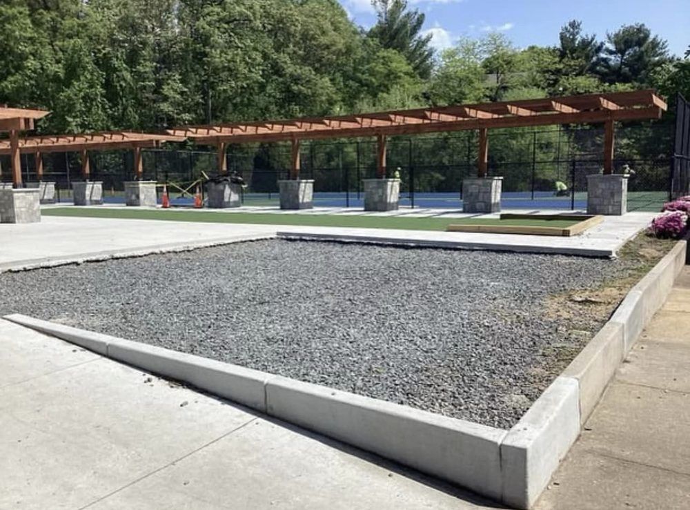 A gravel area with a pergola in the background