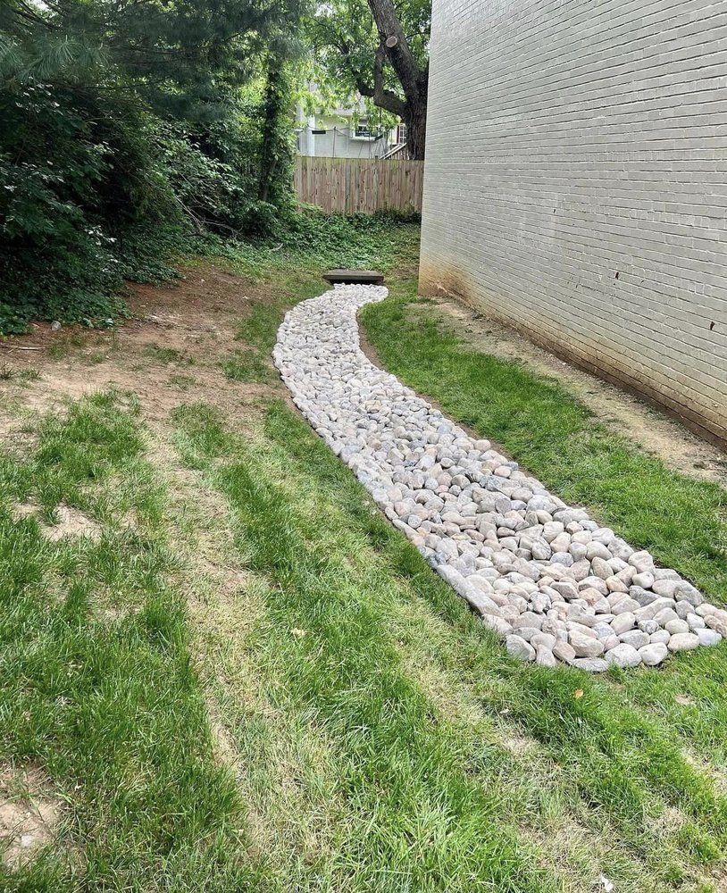 A path made of rocks in the grass leading to a house.
