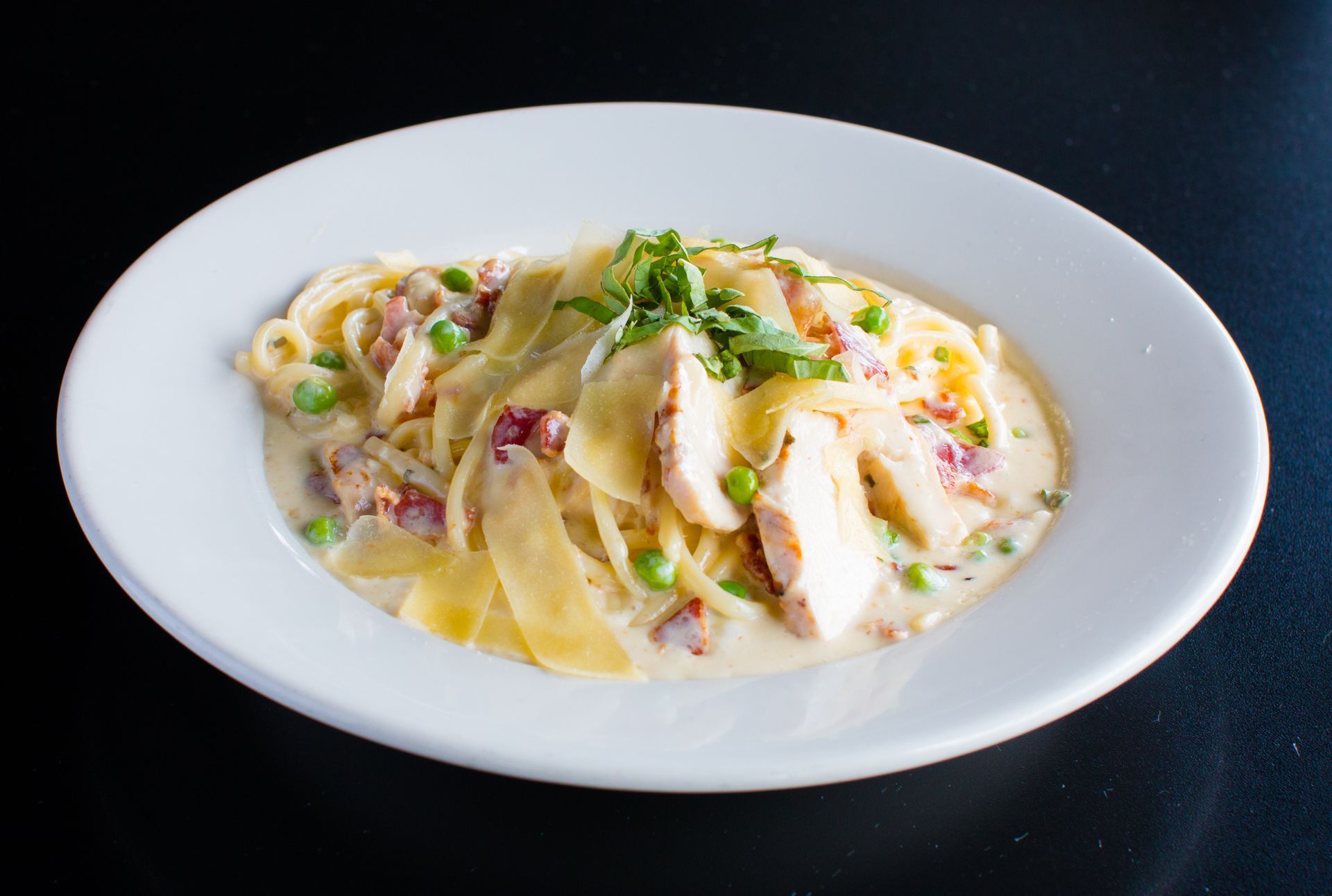 A white plate topped with noodles chicken and peas.