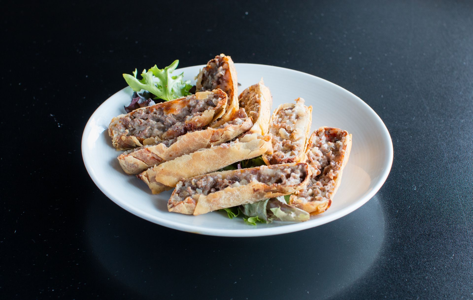 A white plate topped with fried food and lettuce on a black table.