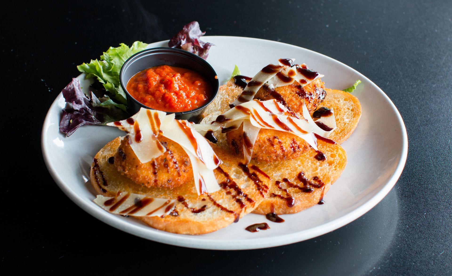 A white plate topped with fried food and a bowl of sauce.