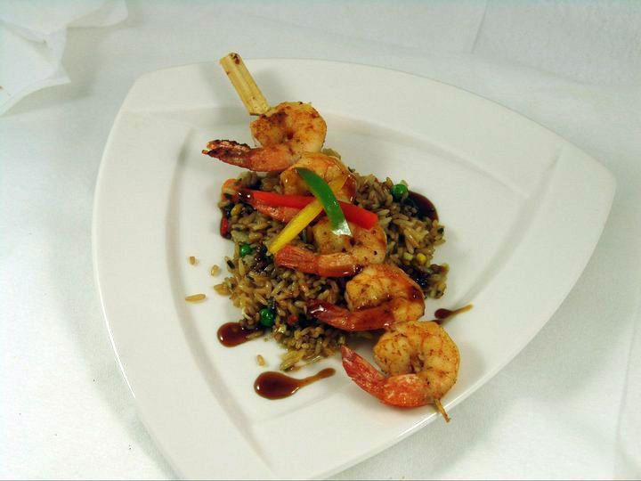 A white plate topped with shrimp rice and vegetables.