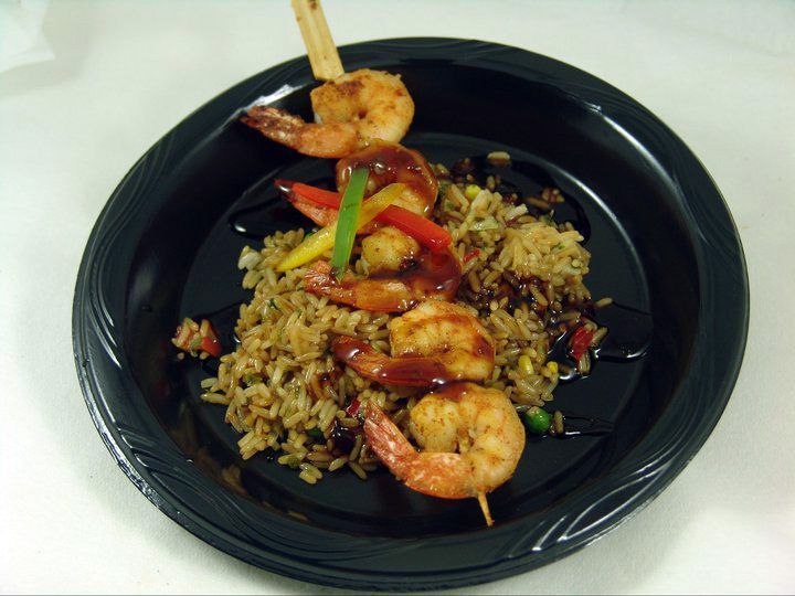 A black plate topped with shrimp and rice.