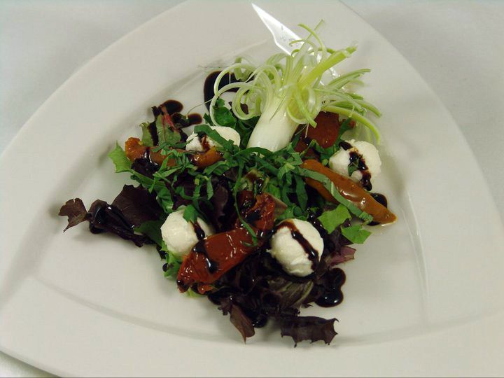 A white plate topped with a salad with mozzarella and tomatoes.
