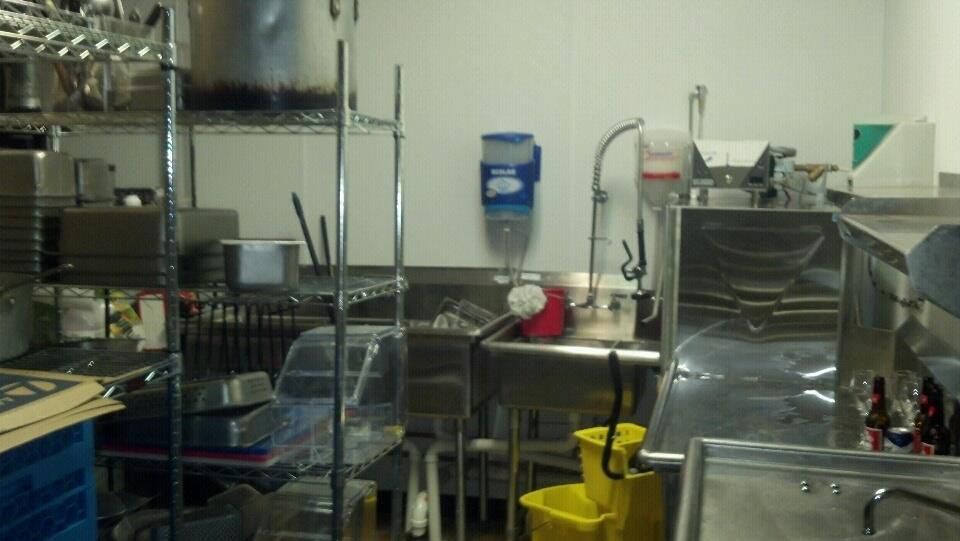 A kitchen with a sink and a bucket in it.