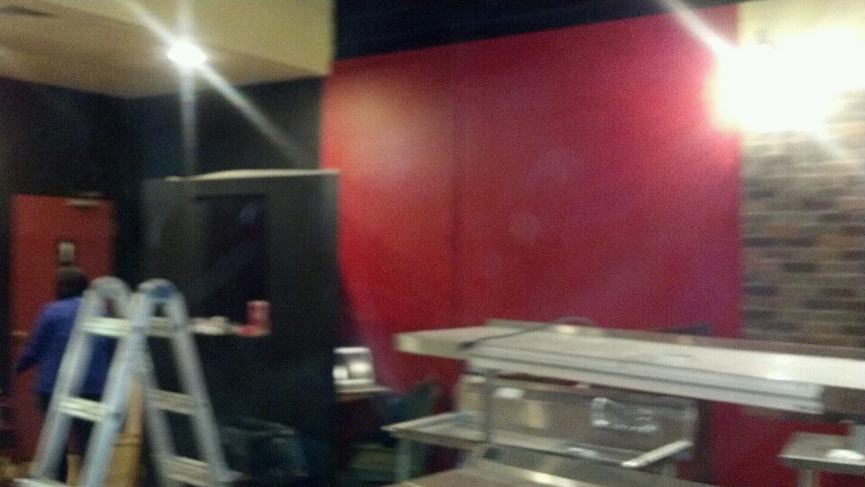 A man is standing next to a ladder in a room with red walls.