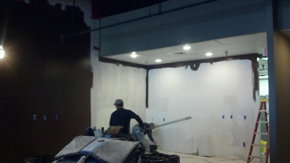 A man is working on a wall in a dark room.