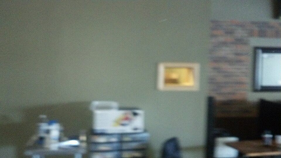 A blurry picture of a living room with a picture on the wall.