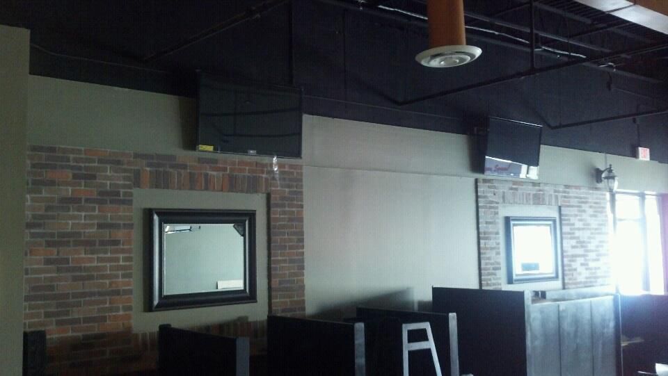 A room with a brick wall and a mirror with the letter a on it.