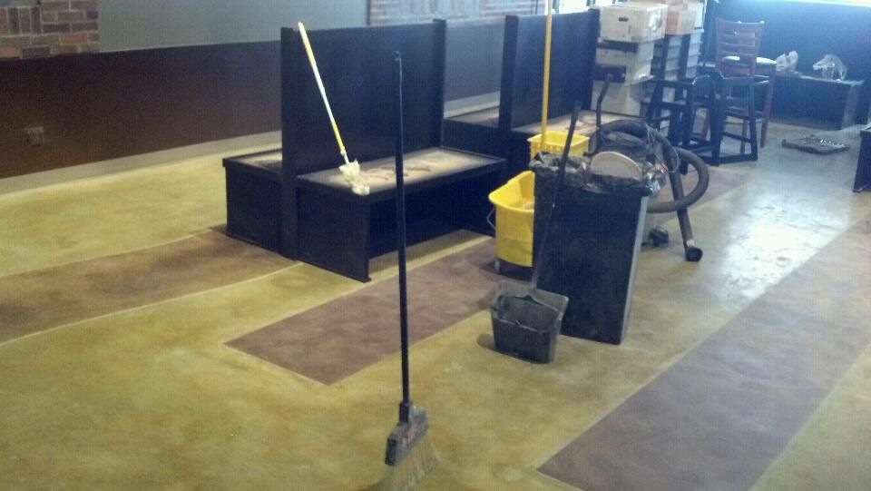 A mop and broom are sitting on the floor of a restaurant.