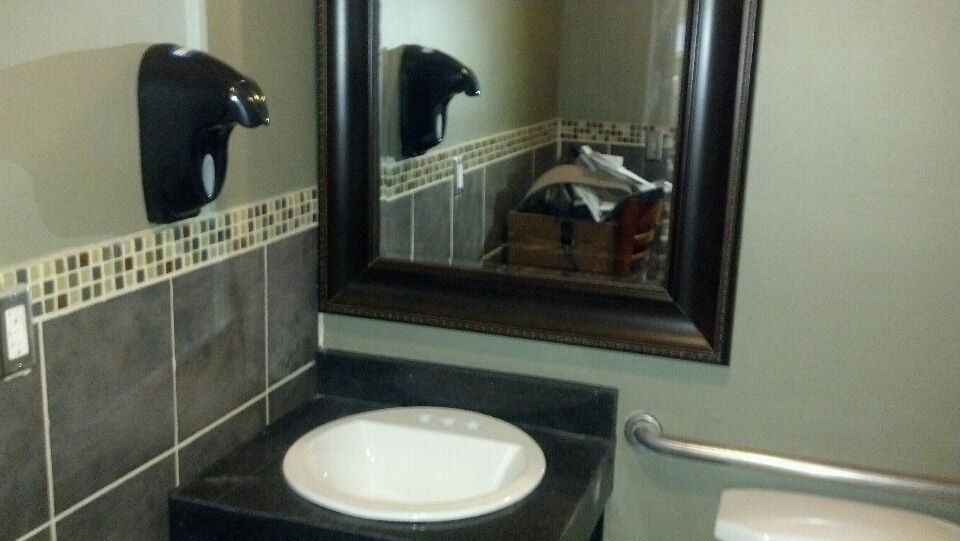 A bathroom with a sink a toilet and a mirror.