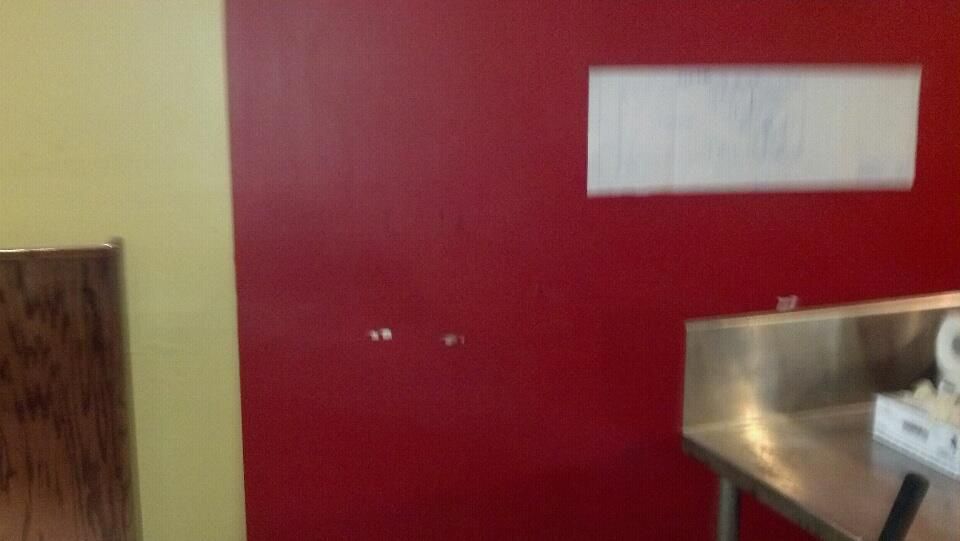 A kitchen with a red wall and a stainless steel counter top.