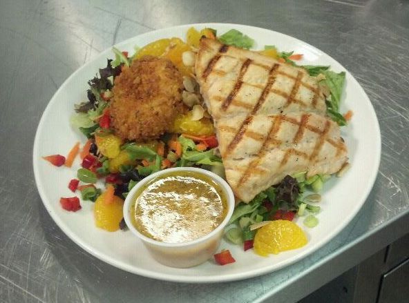 A plate of food with a small cup of sauce on the side.