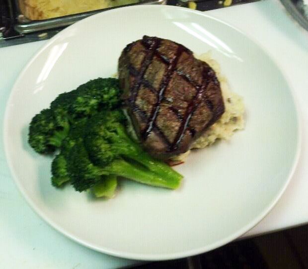A white plate topped with broccoli and a steak.