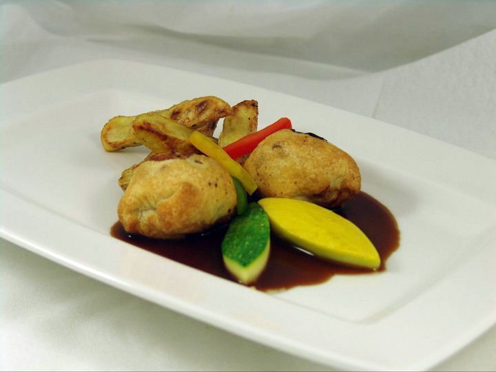 A white plate topped with meat and vegetables on a table.