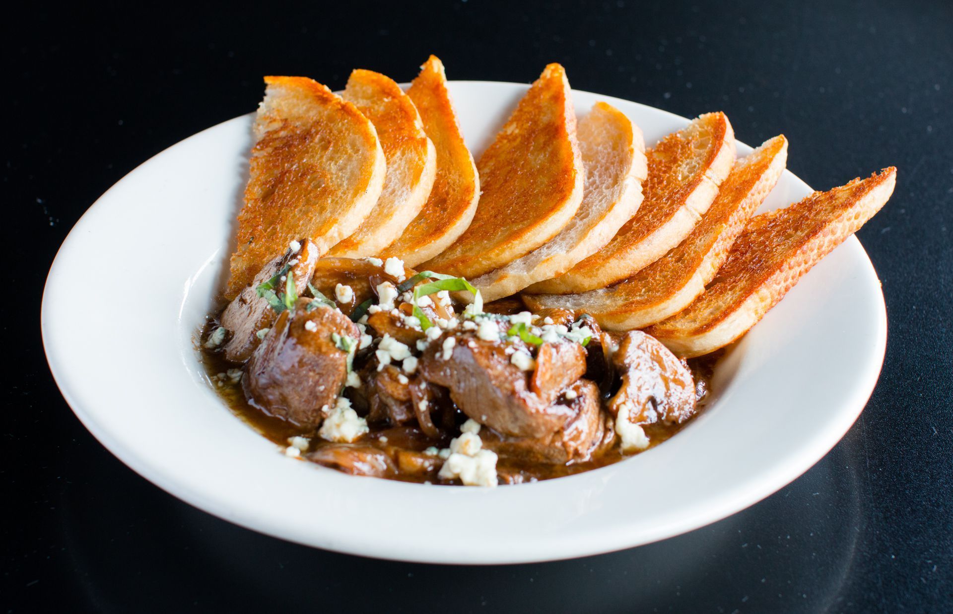 A white plate topped with meat and bread on a table.