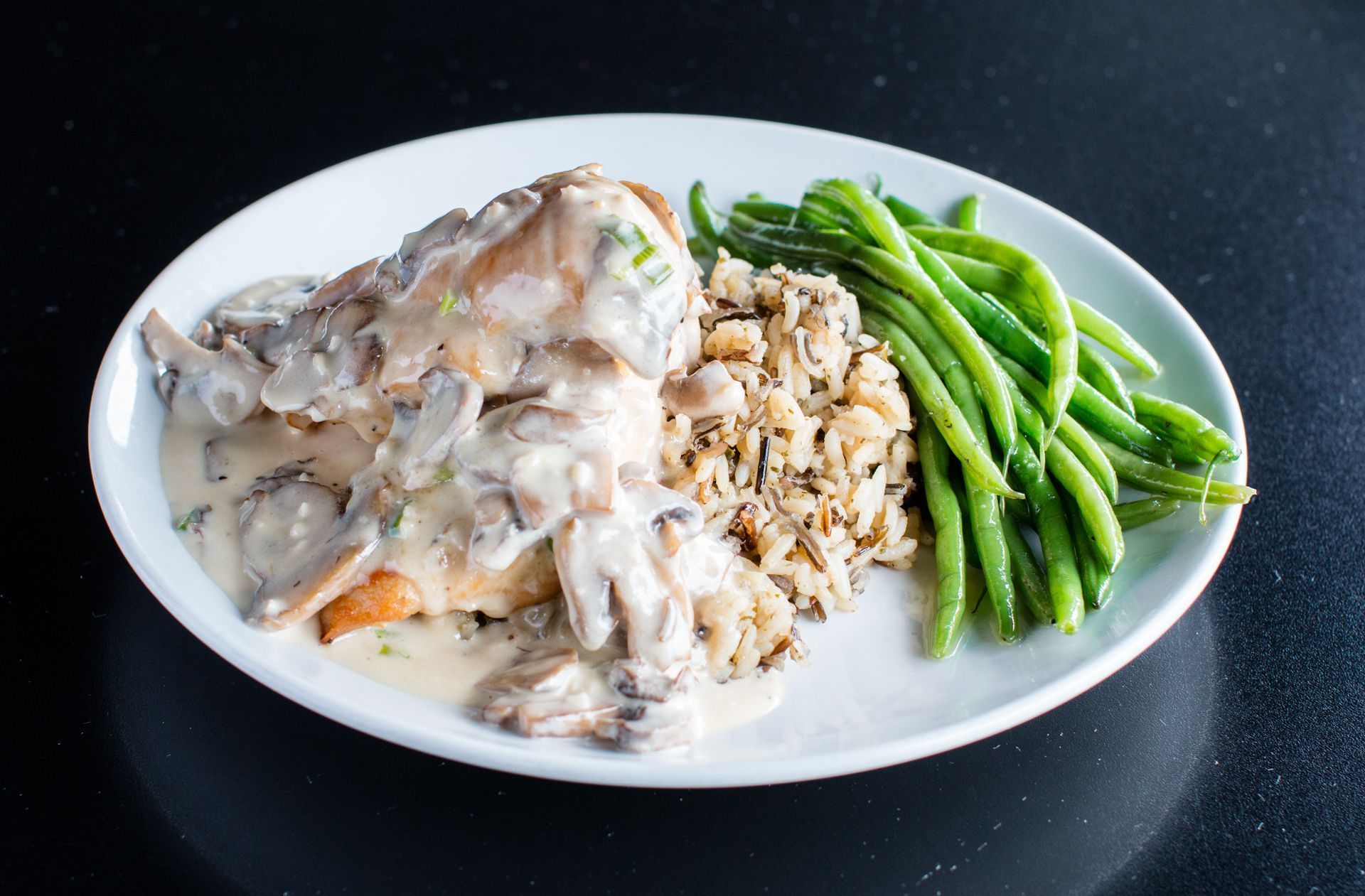 A plate of food with rice and green beans on a table.
