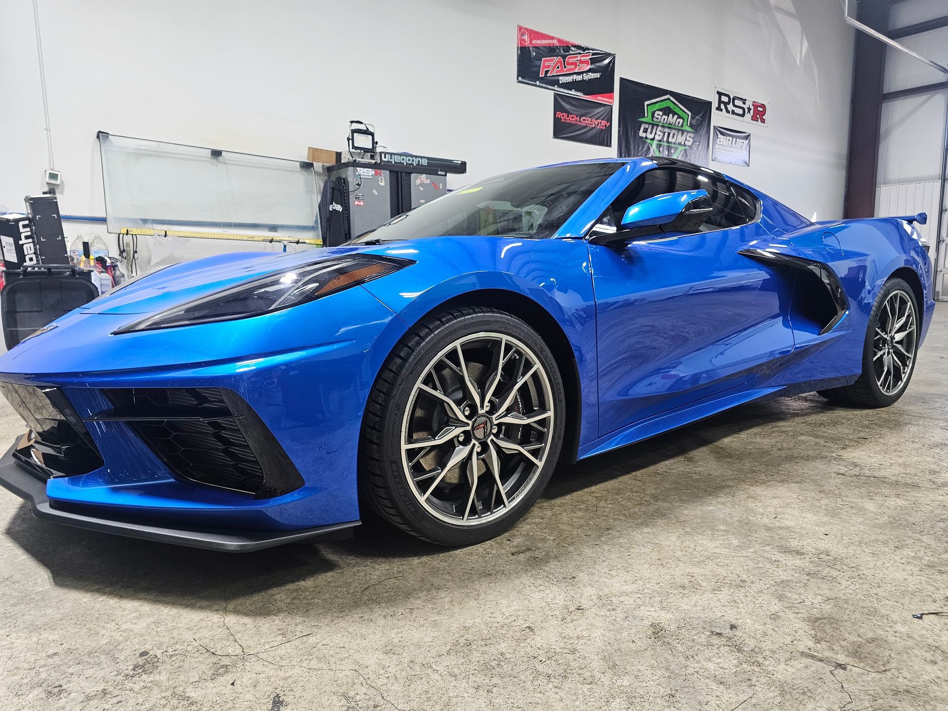 A person is wrapping a car in purple and green foil.