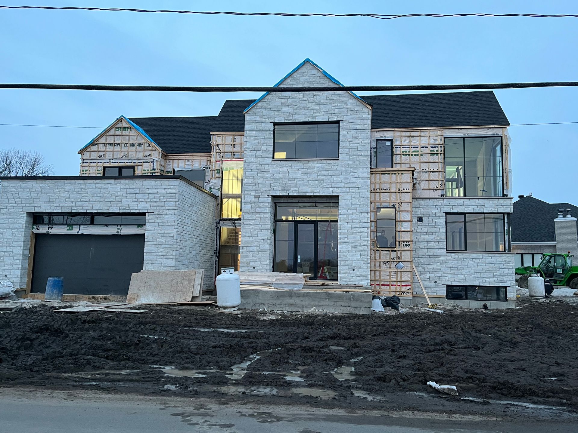 Une grande maison blanche est en construction au milieu d'un champ de terre.
