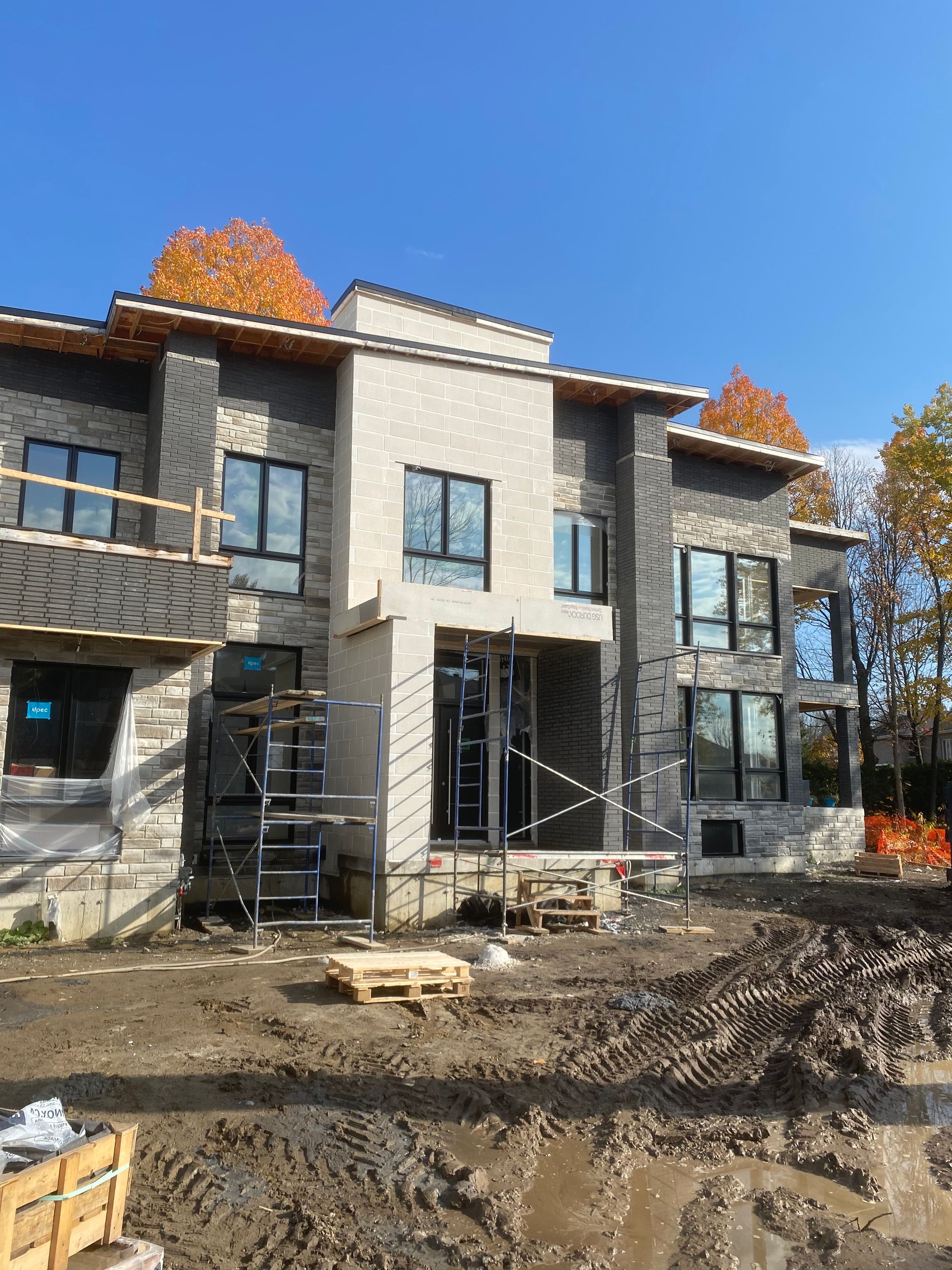 Une grande maison est en construction au milieu d'un champ de terre.