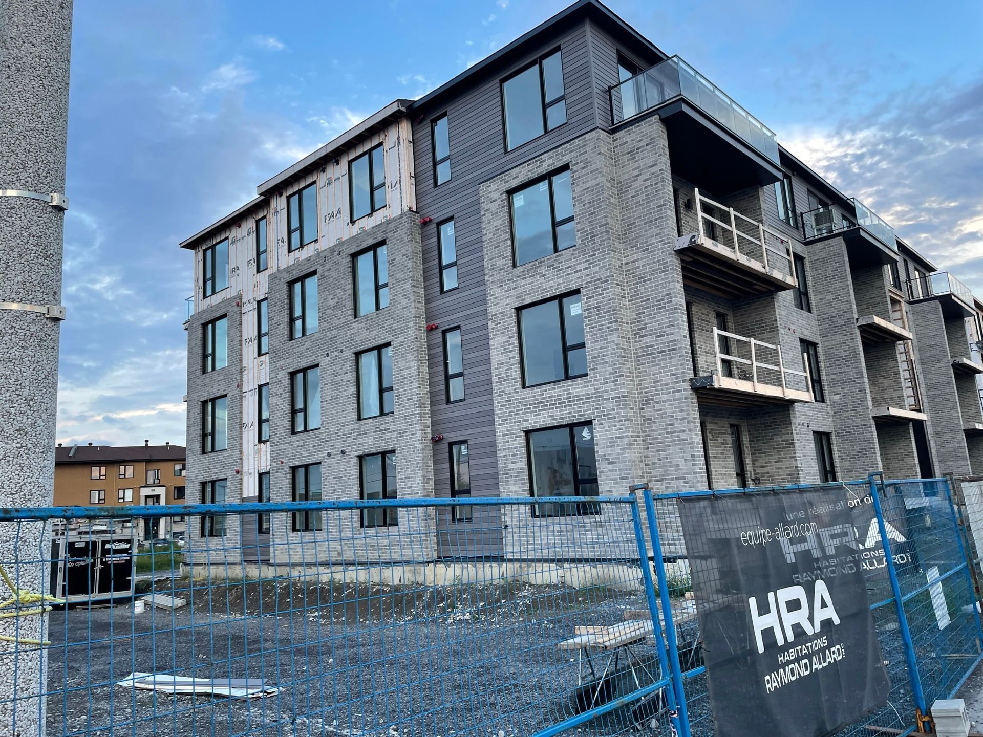 Un grand bâtiment en brique en construction avec une pancarte devant lui.