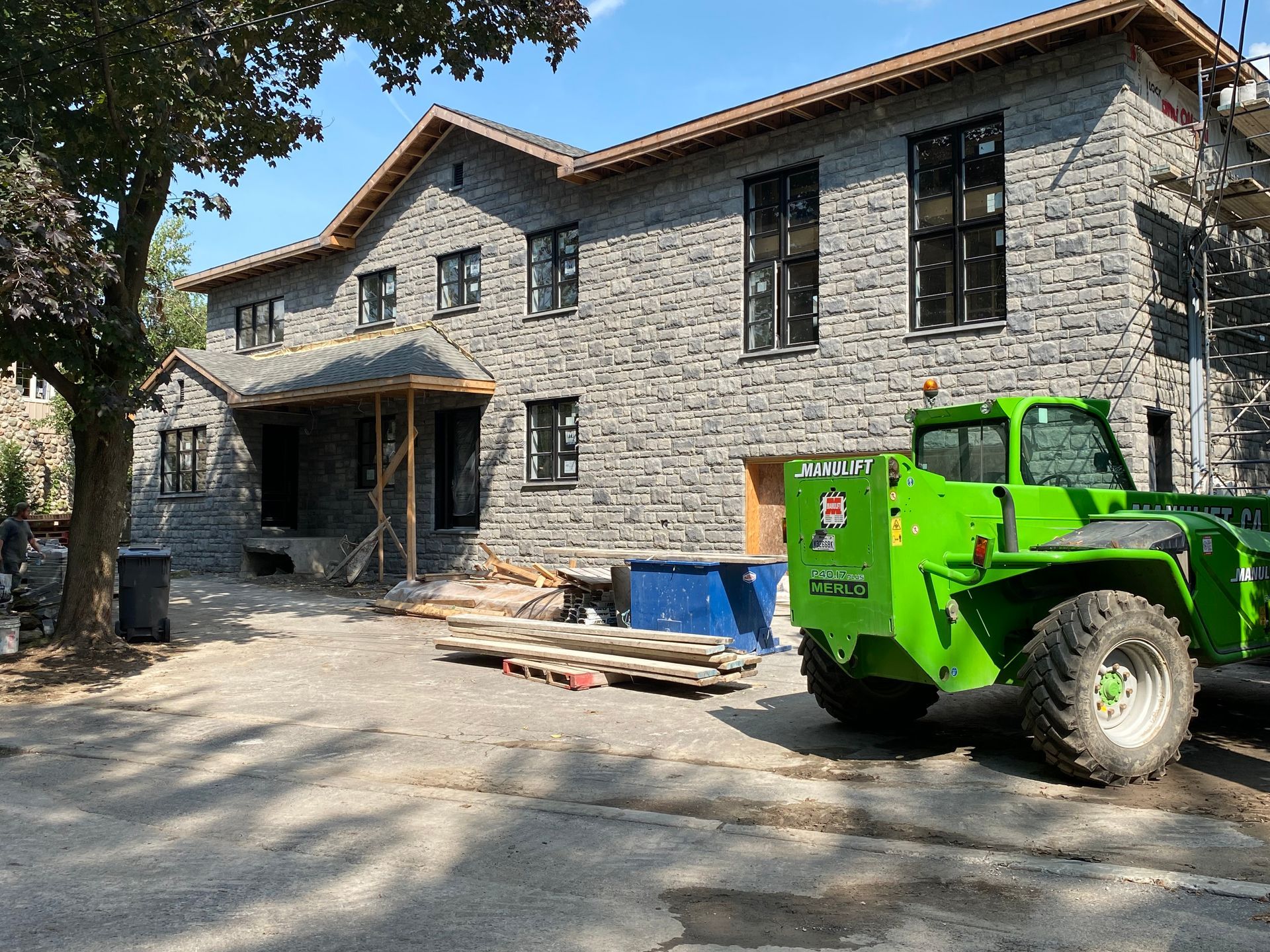 Un chariot élévateur vert est garé devant un grand bâtiment en brique