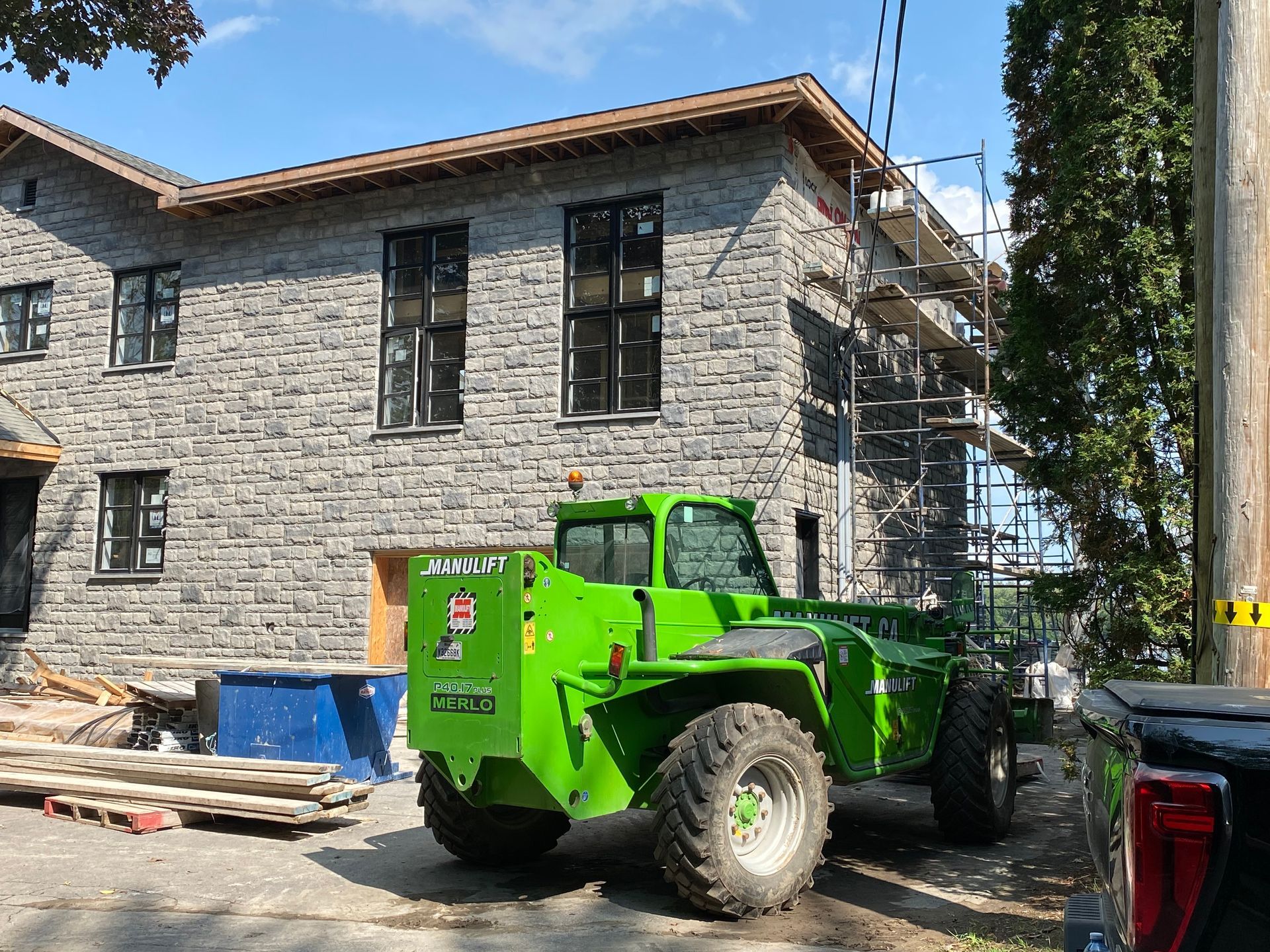 Un tracteur vert est garé devant un bâtiment en brique en construction.