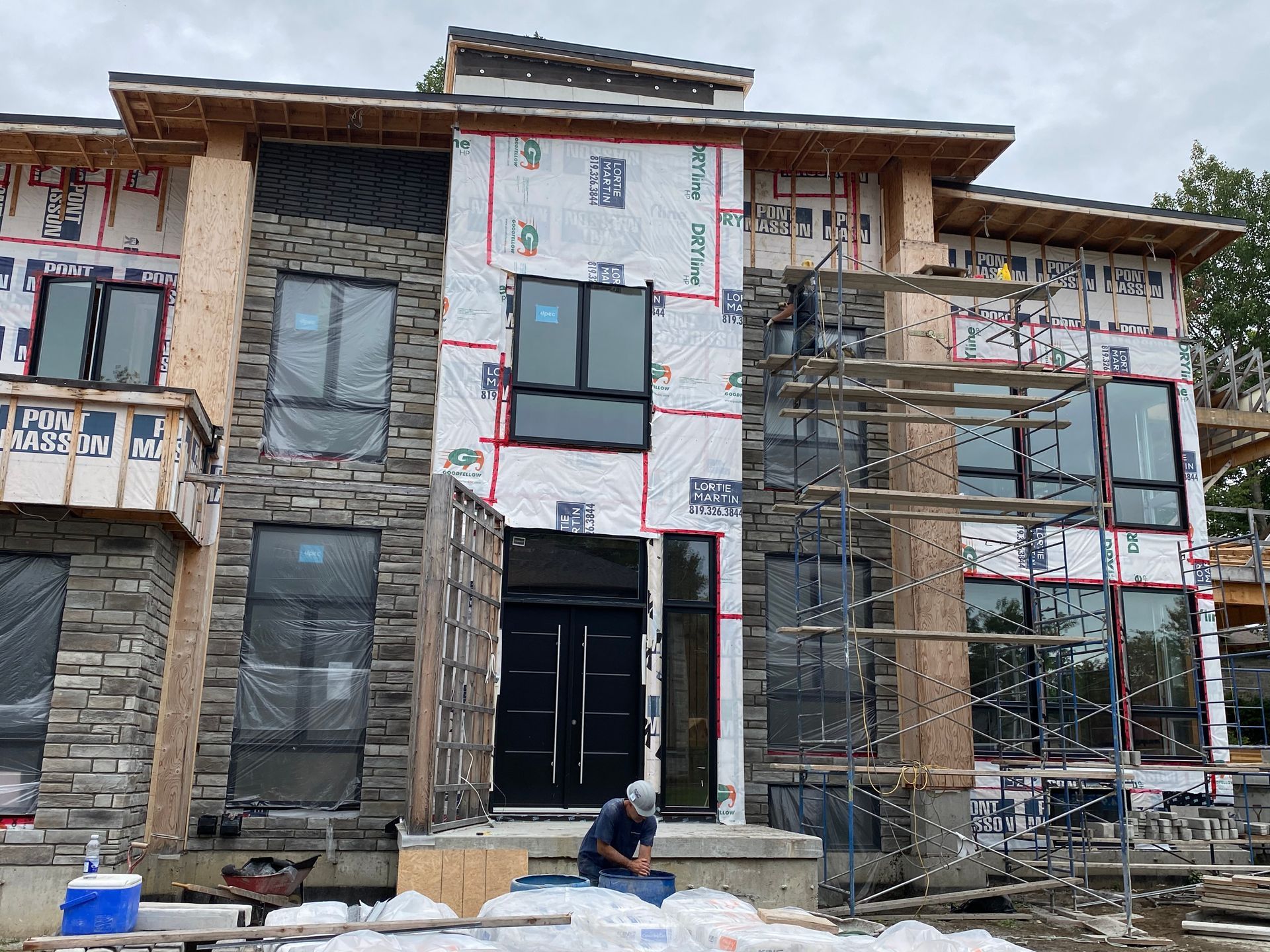 Un homme est assis devant une grande maison en construction.