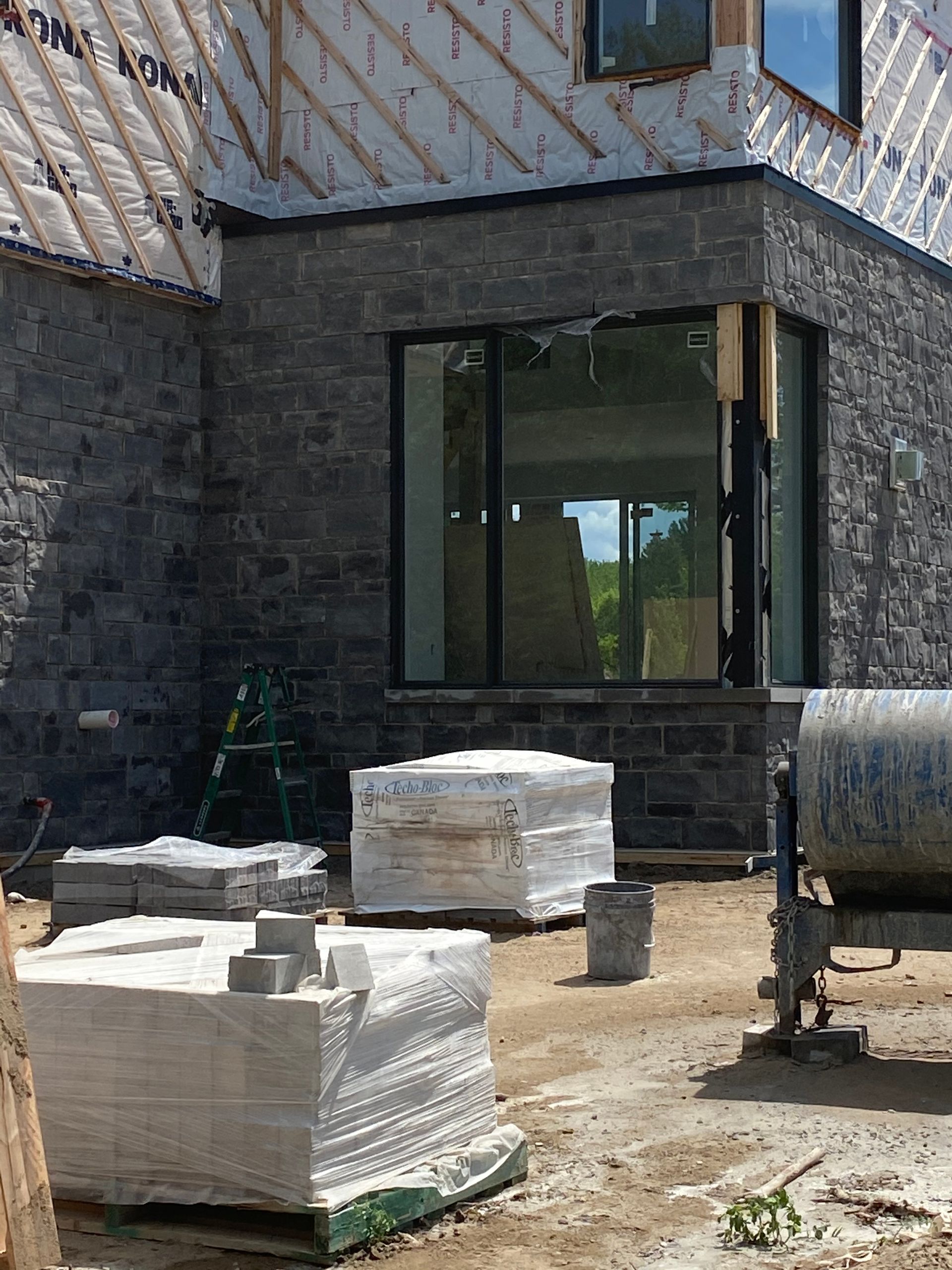 Une maison est en construction avec beaucoup de briques devant.