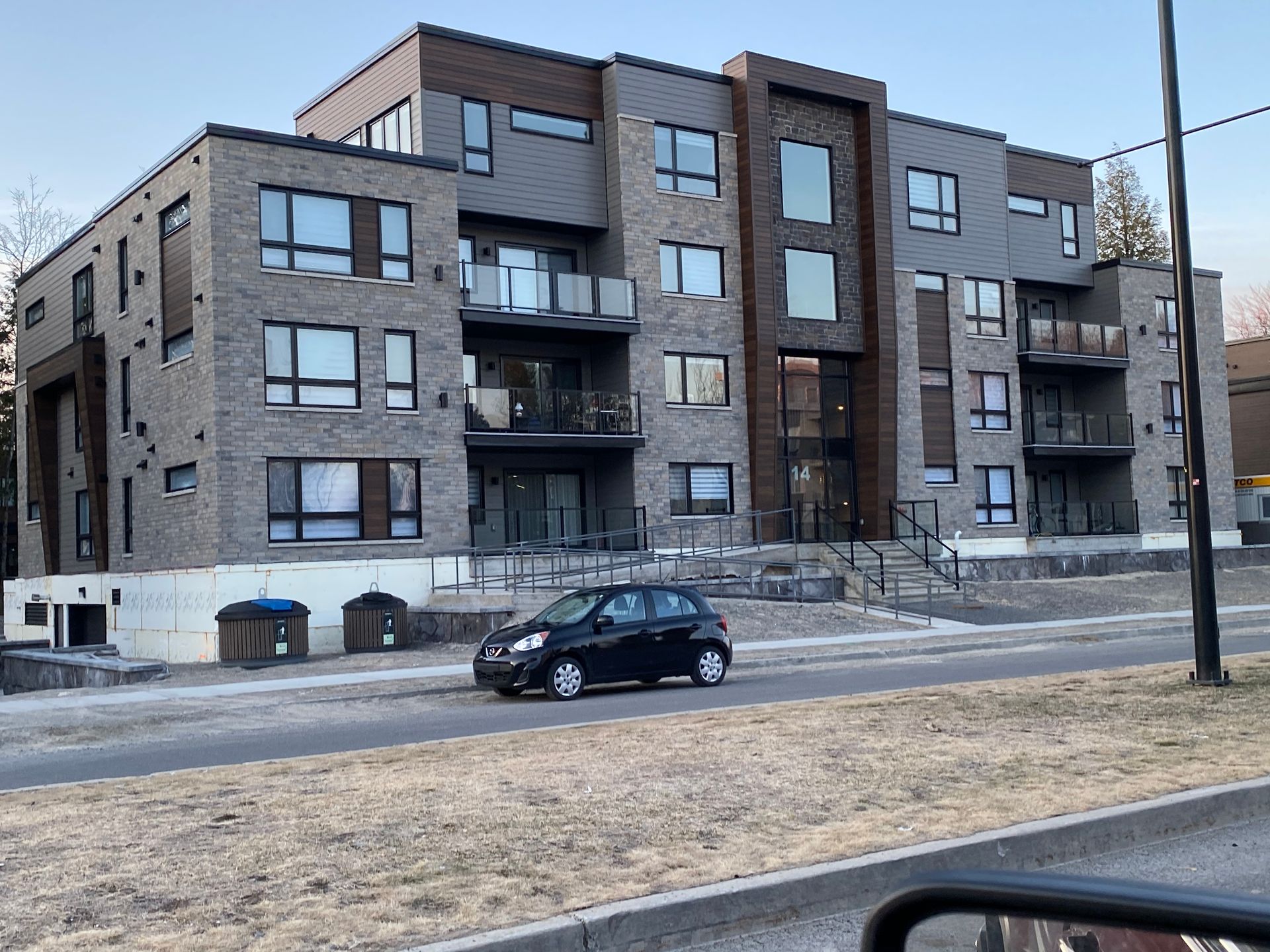 Une voiture est garée devant un grand immeuble.