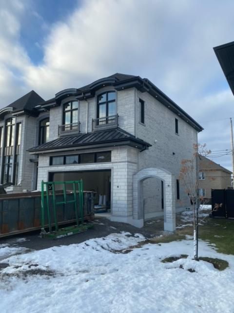 Une maison blanche avec un toit noir est entourée de neige
