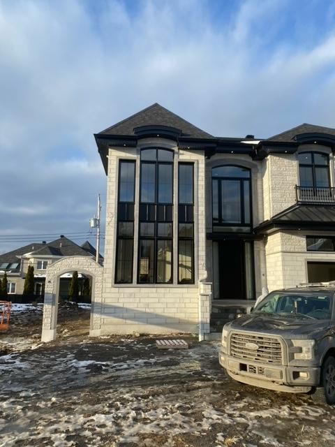 Une grande maison blanche avec un camion noir garé devant