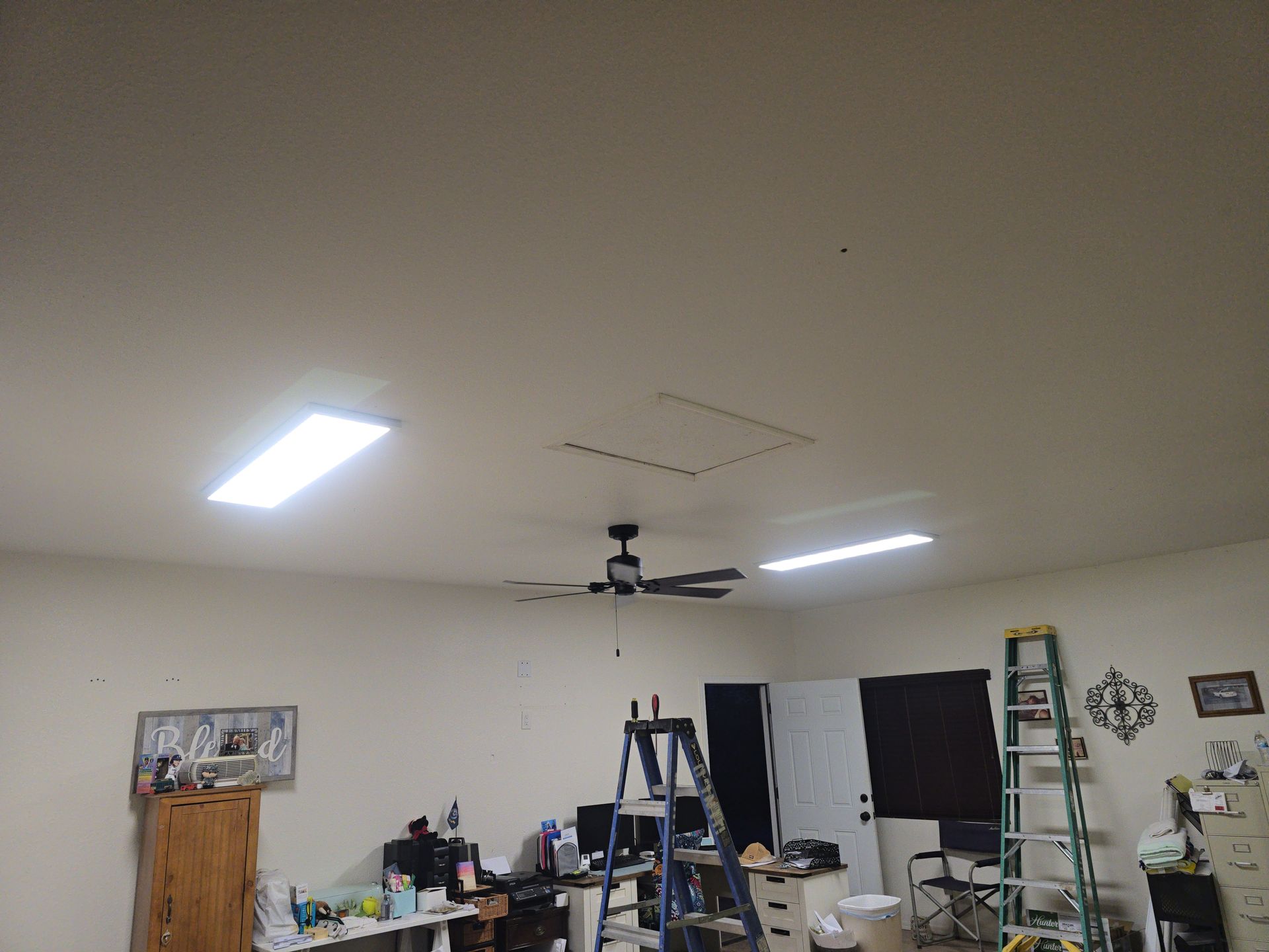 Workshop ceiling with overhead lights, ceiling fan, attic access, and various tools/supplies.