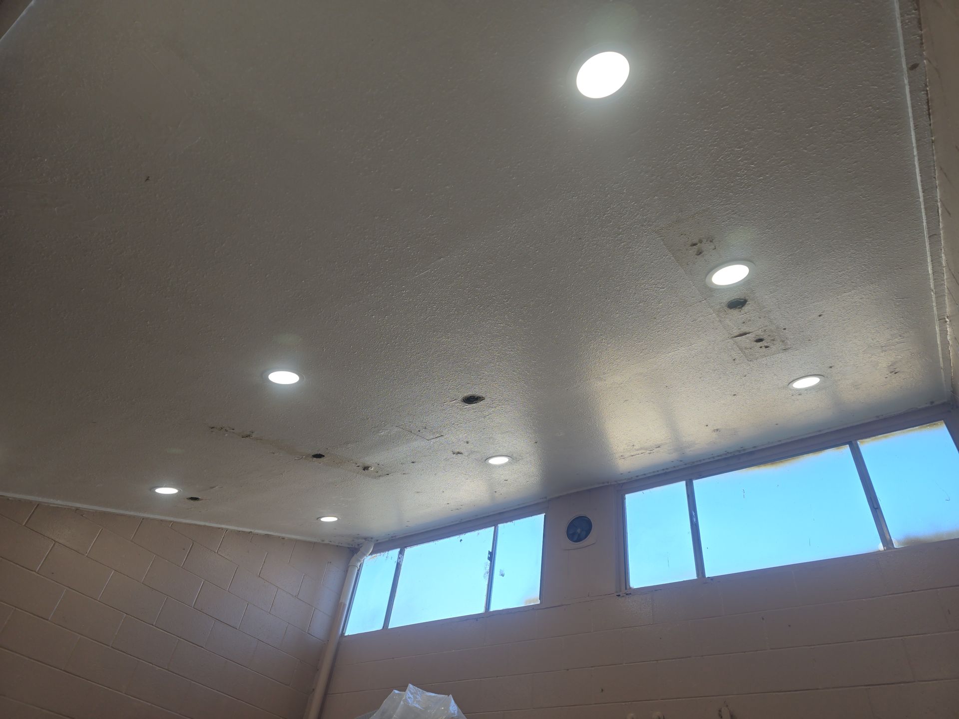 Ceiling with recessed lights, windows, and pale walls.