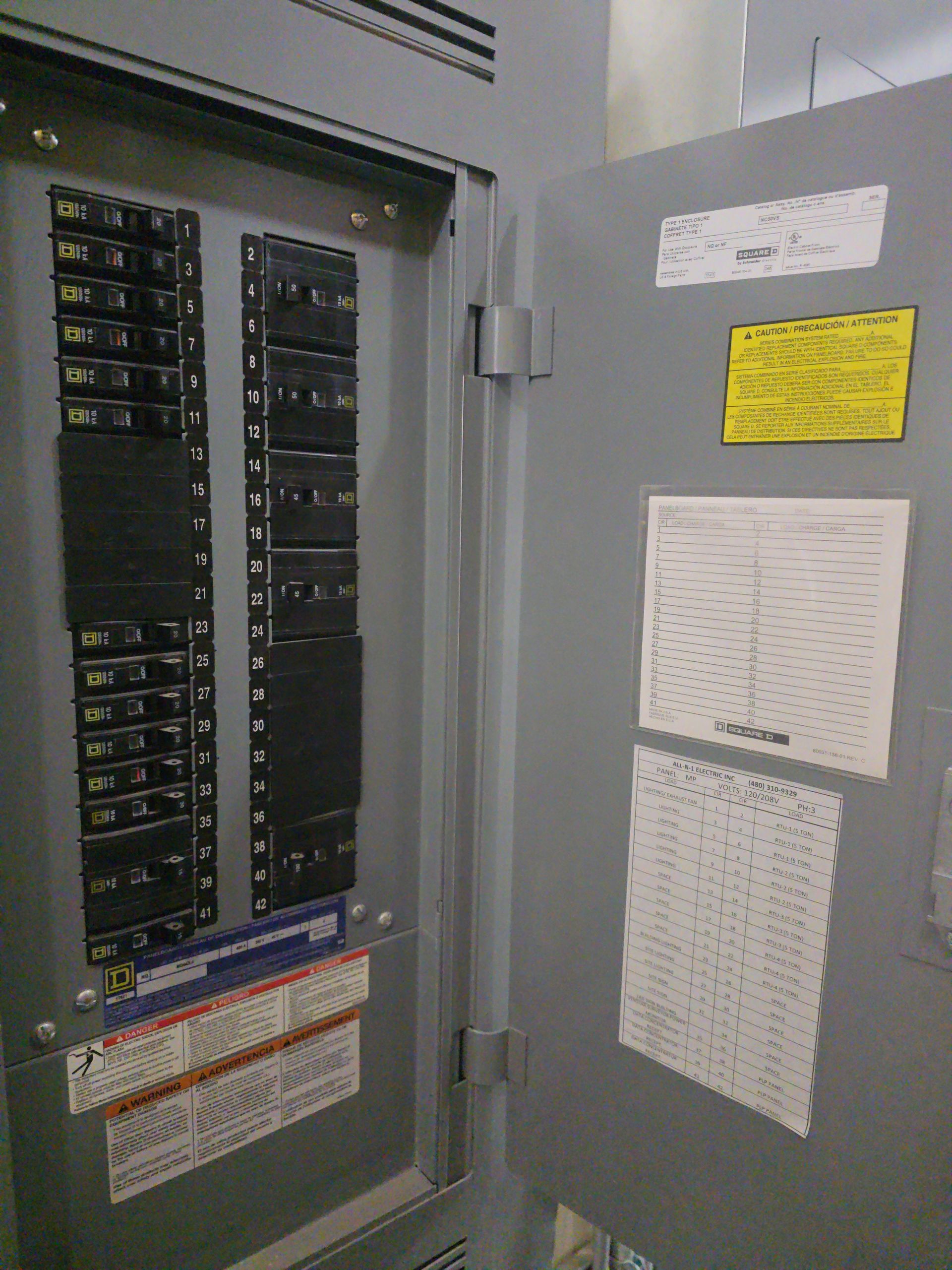 Electrical panel with circuit breakers, door open, labels attached.