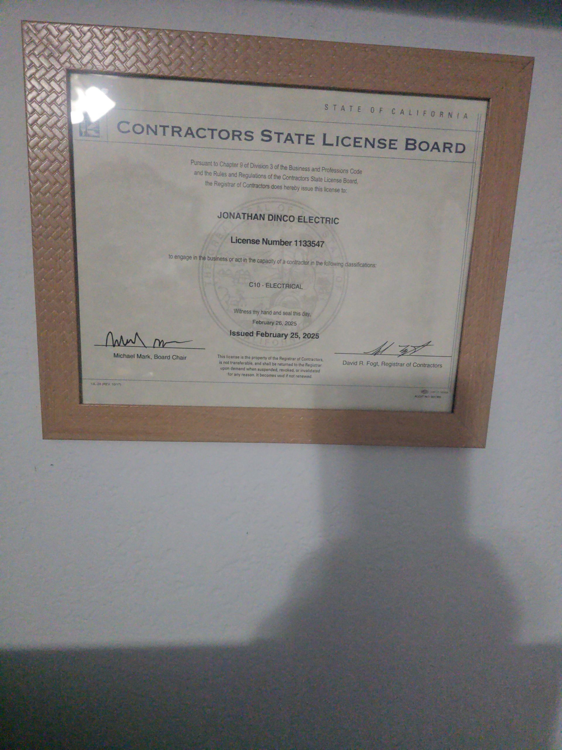 Framed California Contractors State License Board document on a white wall. Beige frame.
