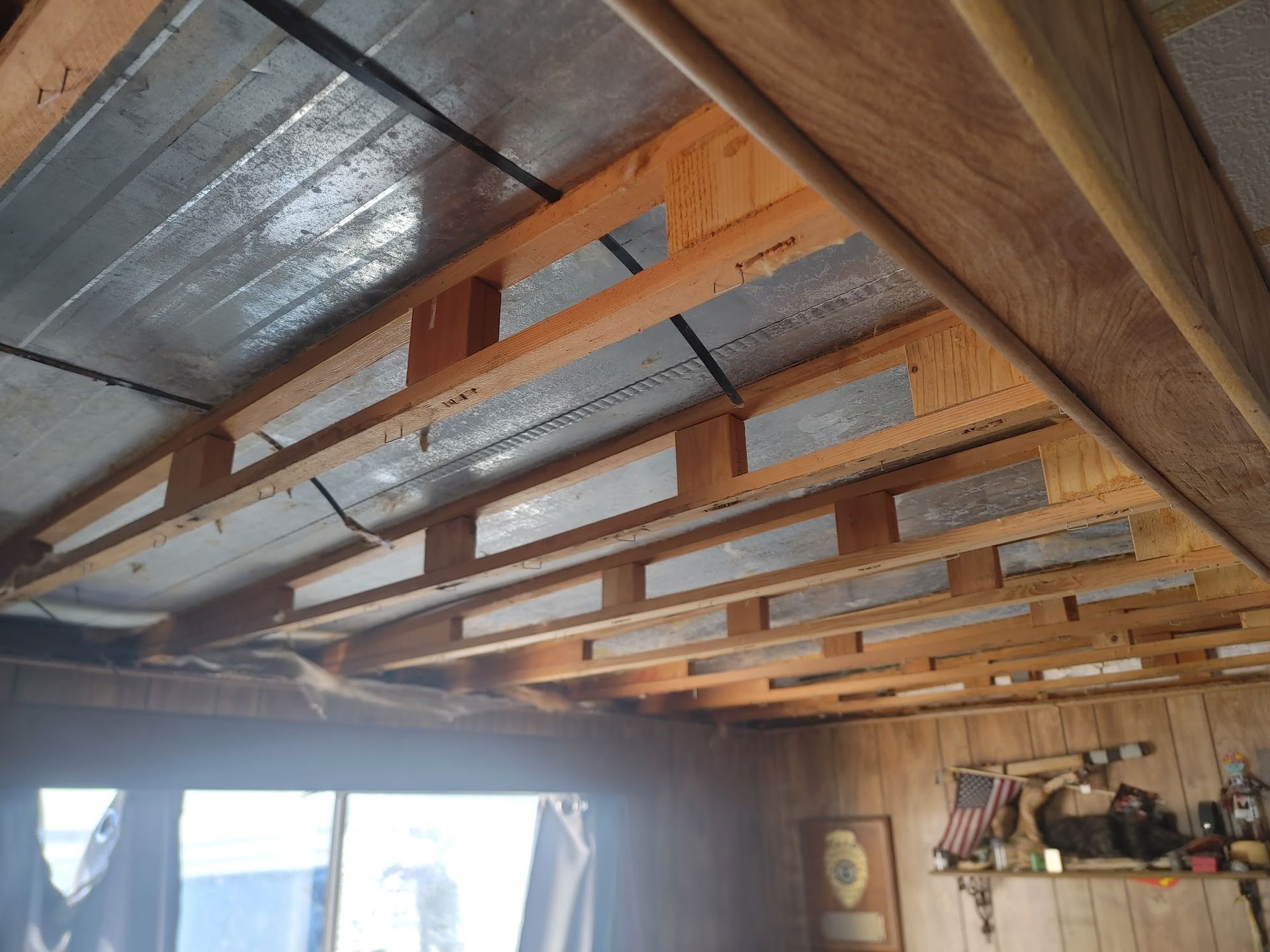 Interior ceiling with exposed wooden beams, reflective insulation, and visible support structure.