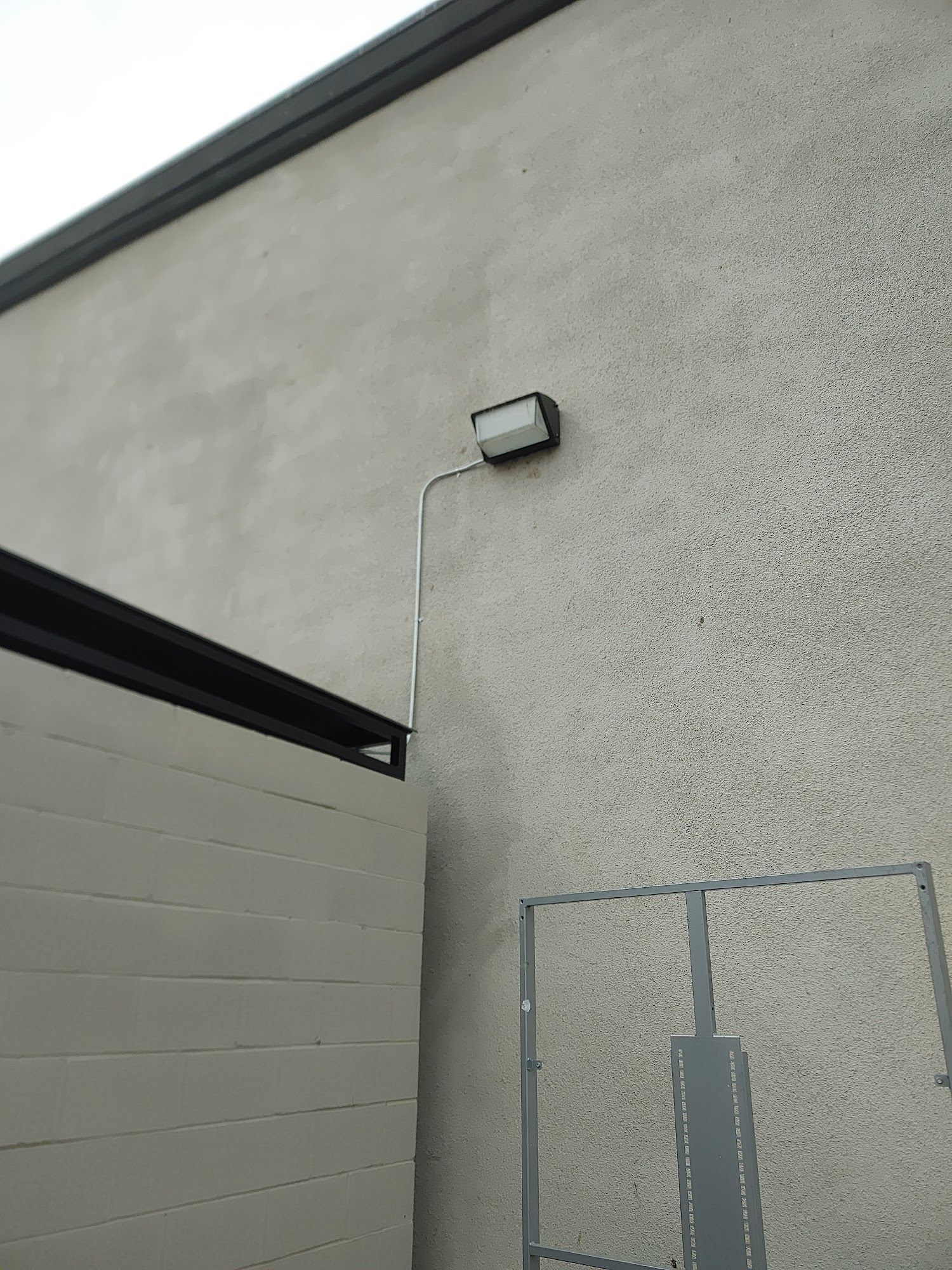 Exterior wall with mounted floodlight and conduit.