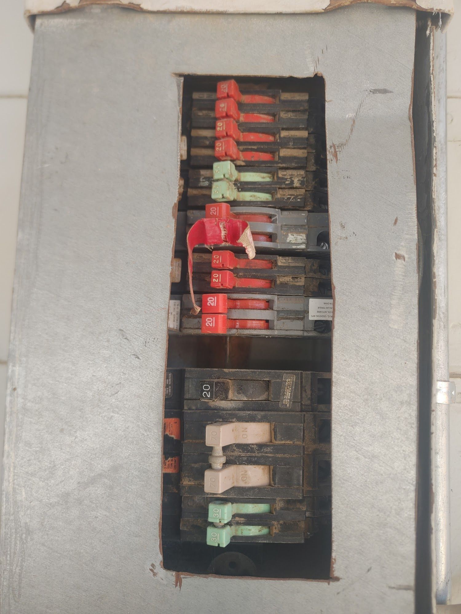 Electrical breaker box with multiple circuit breakers, some red and green, in a metal enclosure.