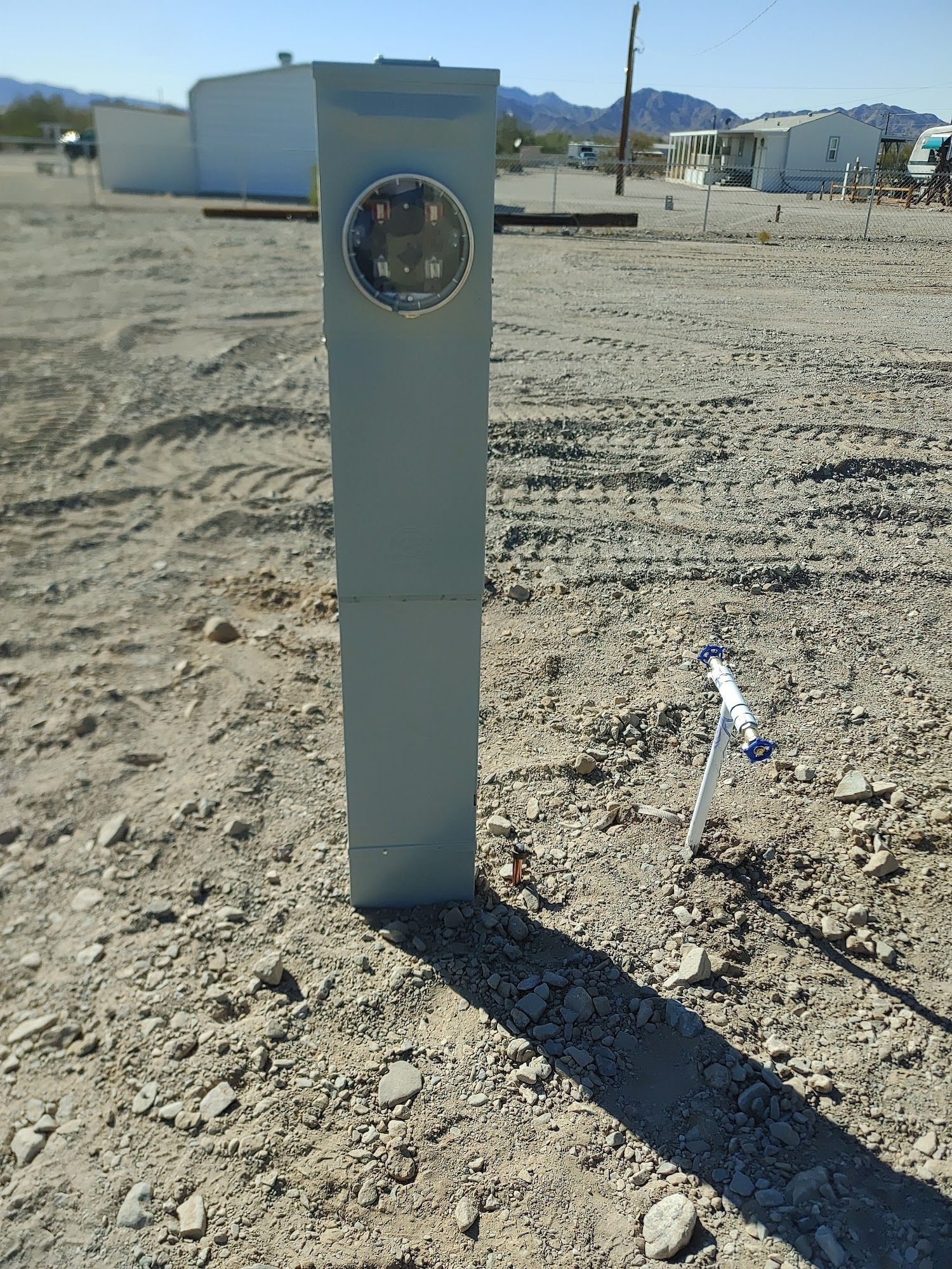 Gray electrical meter box in a dirt field.