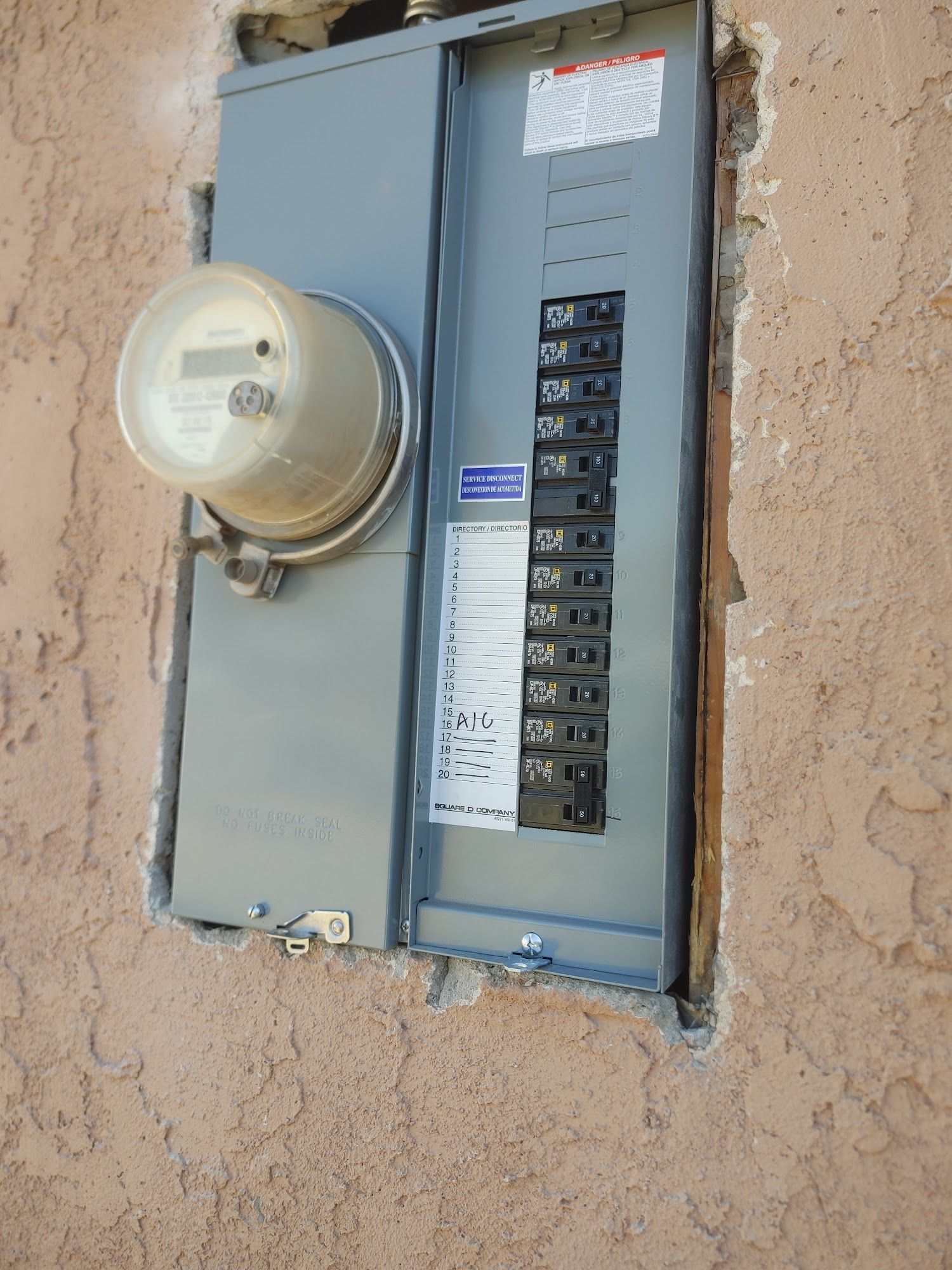 Electrical meter and circuit breaker panel recessed in stucco wall.