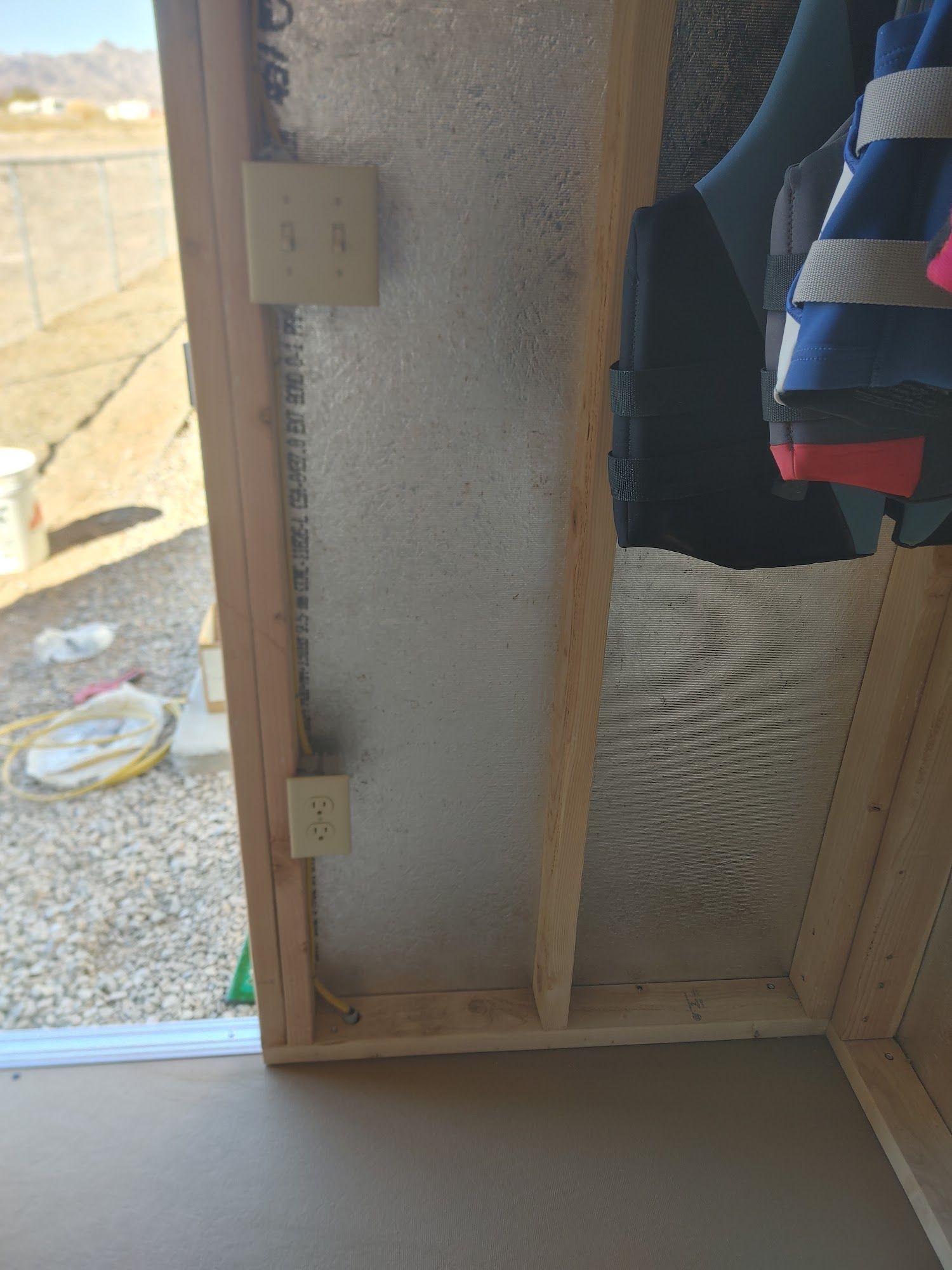 Interior view of a framed wall with electrical outlets and insulation. A window is visible to the left.