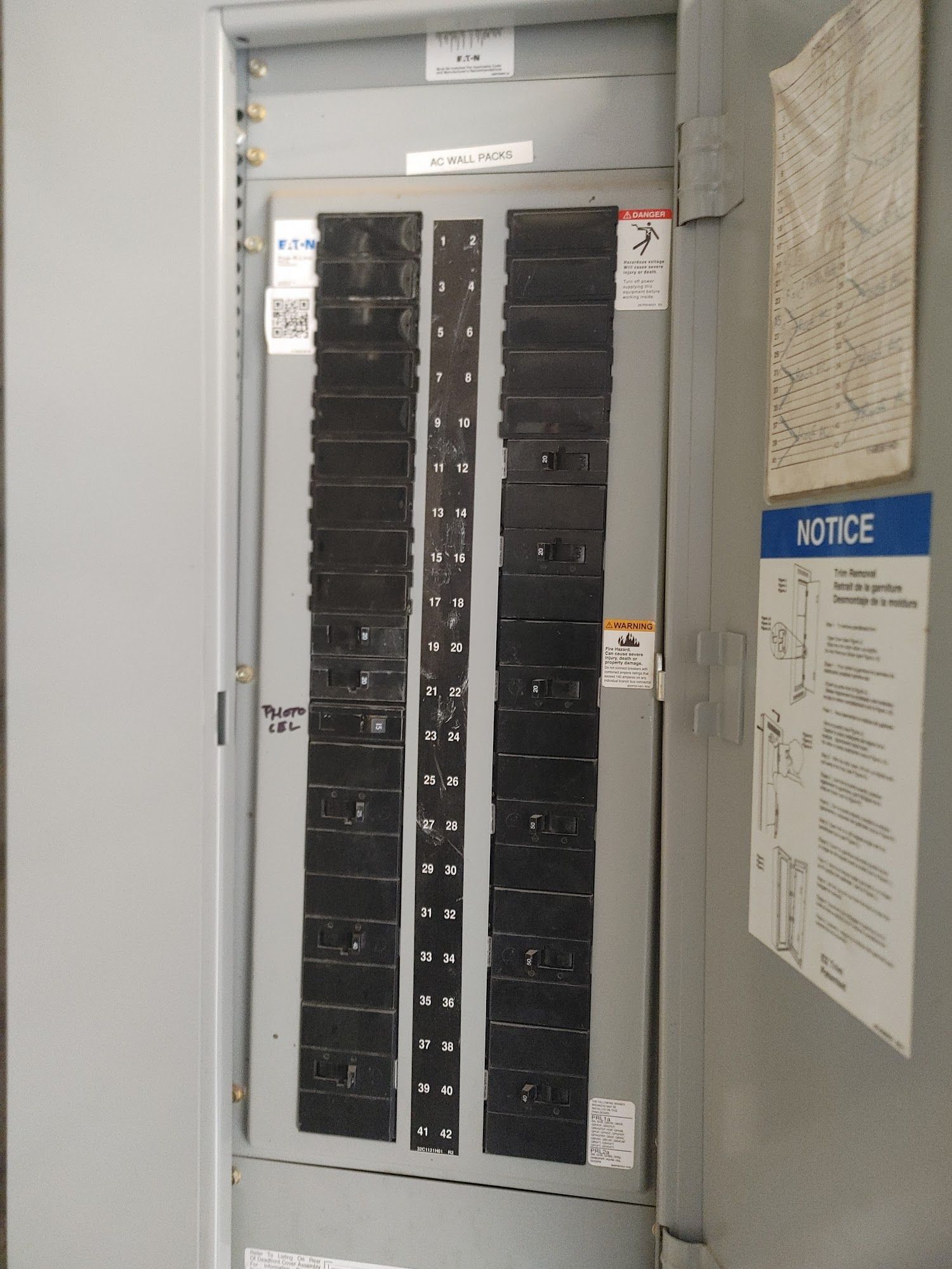 Electrical circuit breaker panel with many black switches inside a metal cabinet.