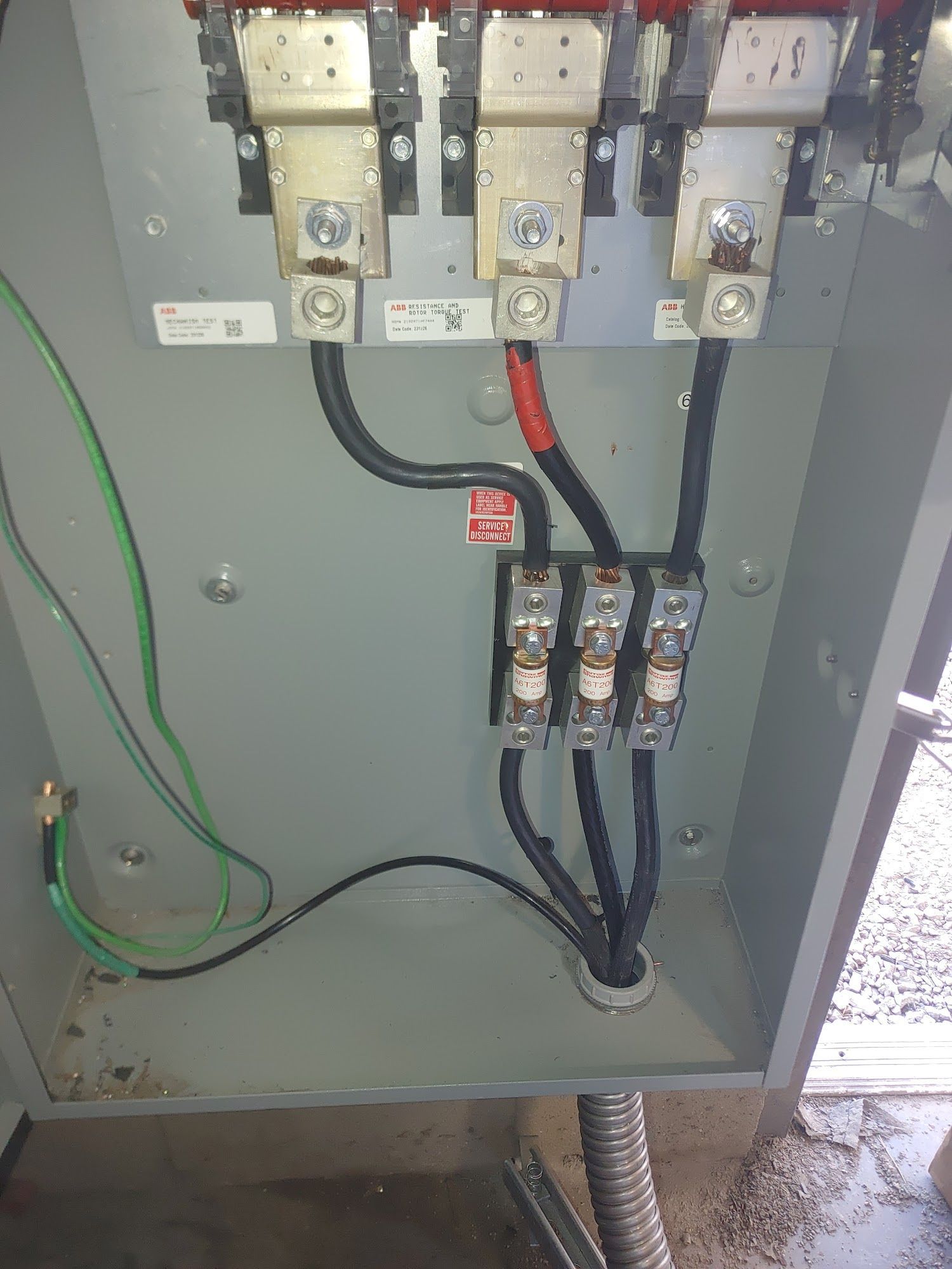 Electrical panel with three black wires connected to fuses and terminals; green grounding wire visible.