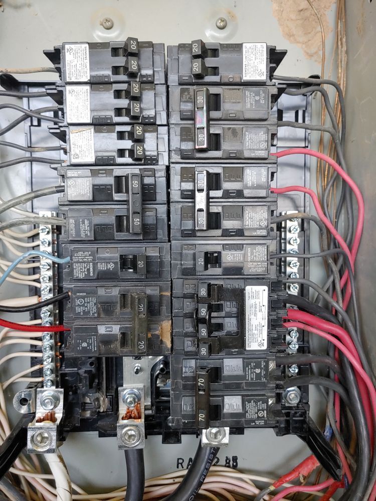 Electrical panel with rows of circuit breakers and wiring.